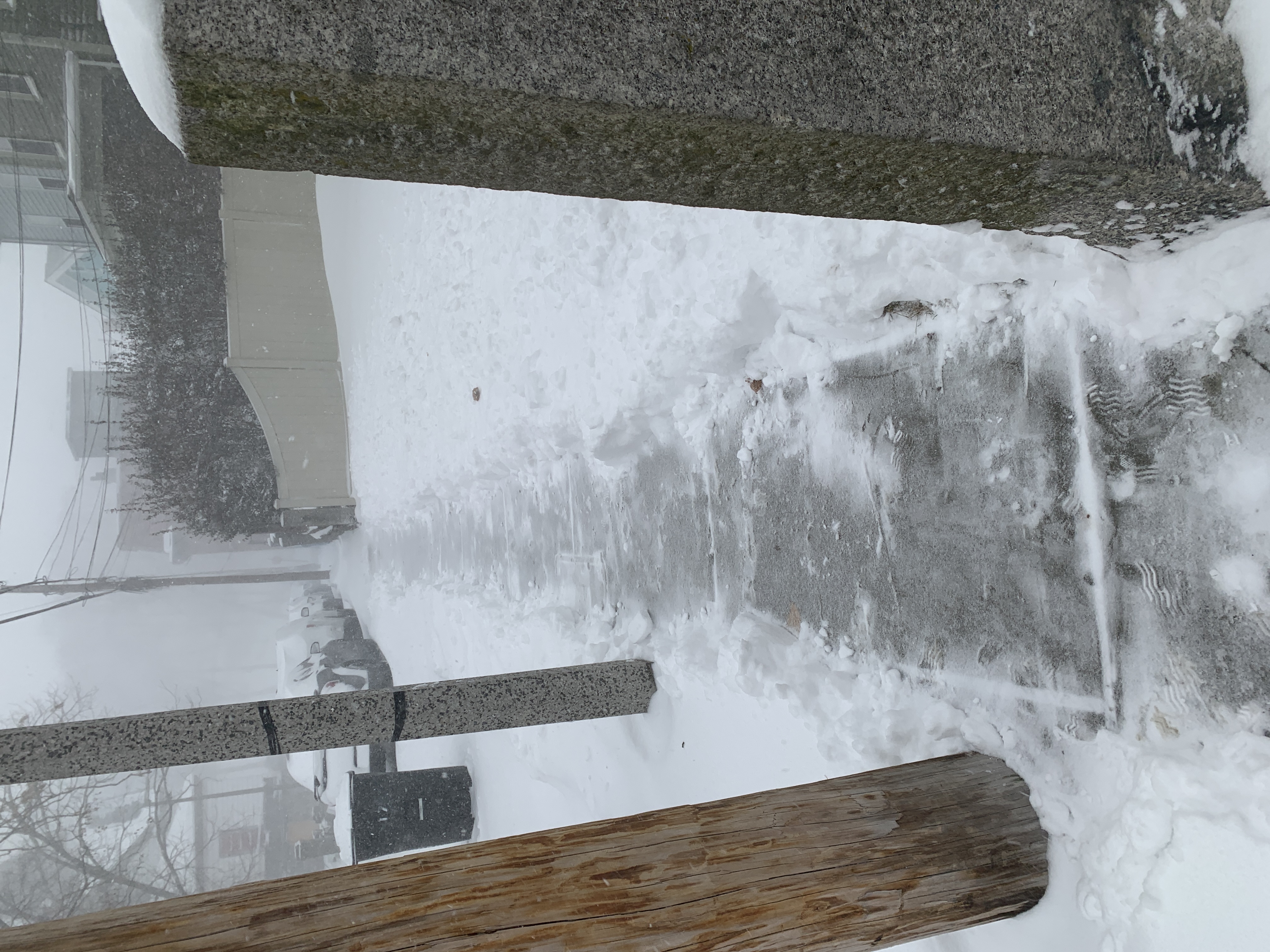 A Roxbury sidewalk cleared down to the pavement during the January 2022 blizzard, with the snow still coming down.